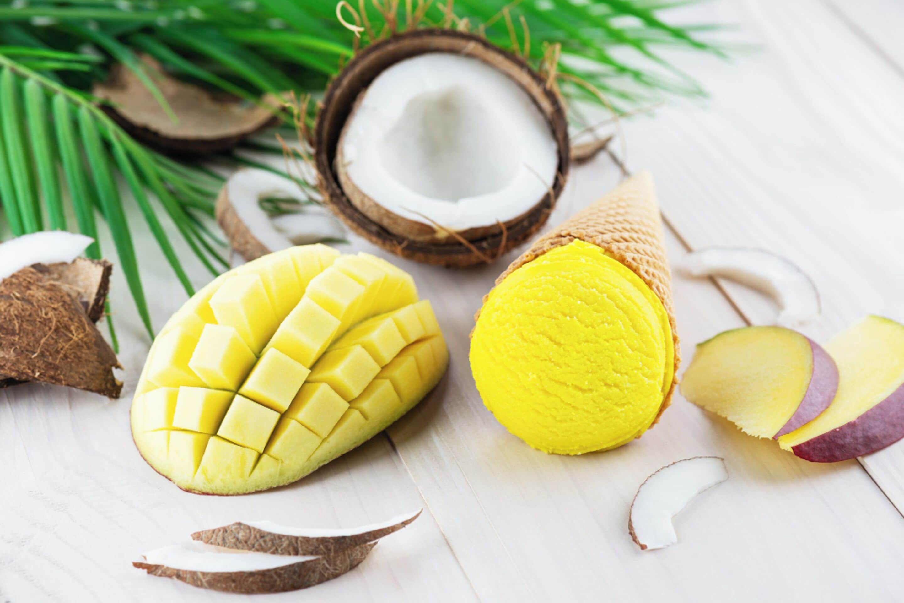 Une mangue et une noix de coco sur une surface blanche.