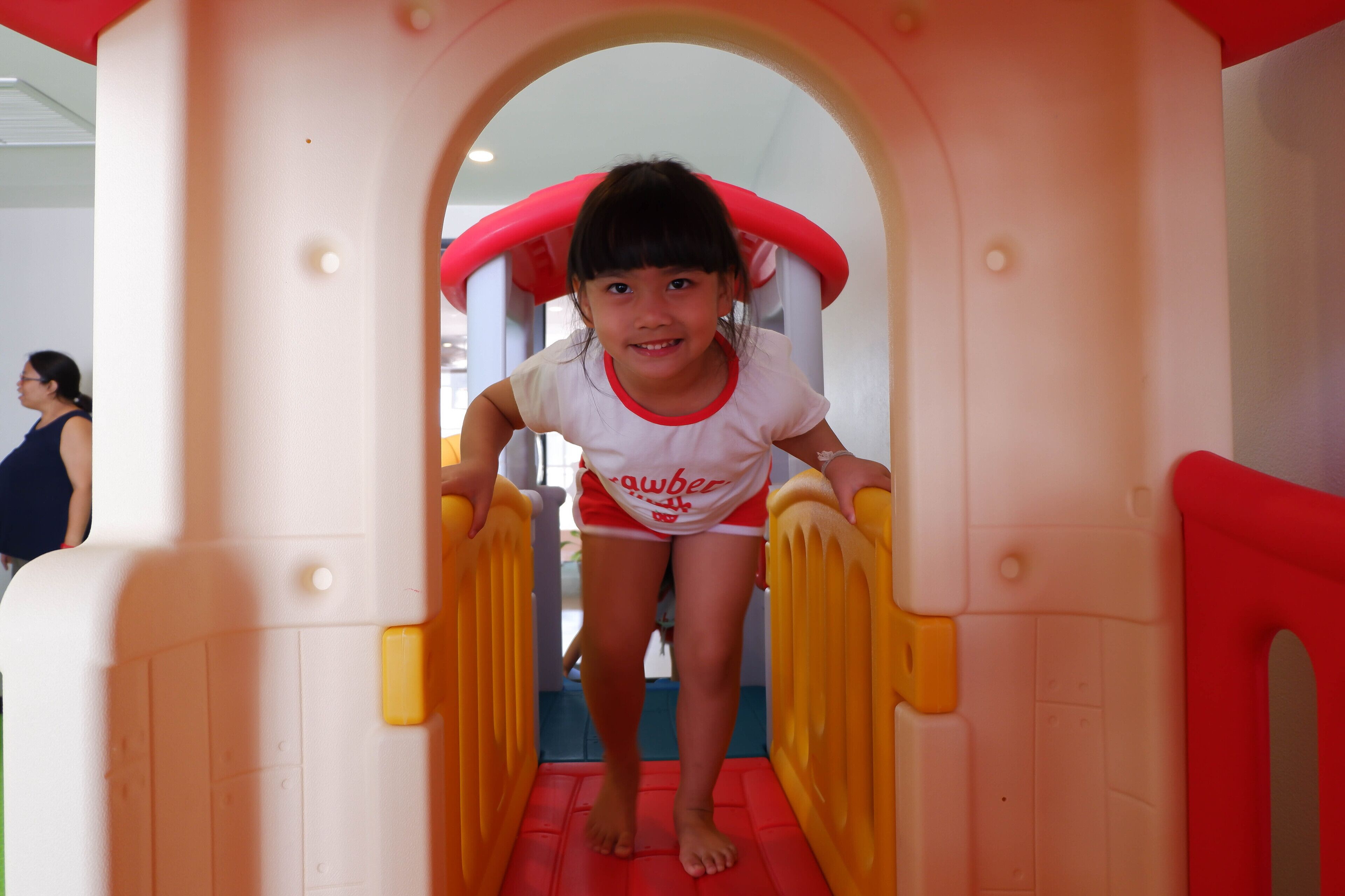 Un niño trepando una estructura de juego de plástico con diseño rojo y amarillo.