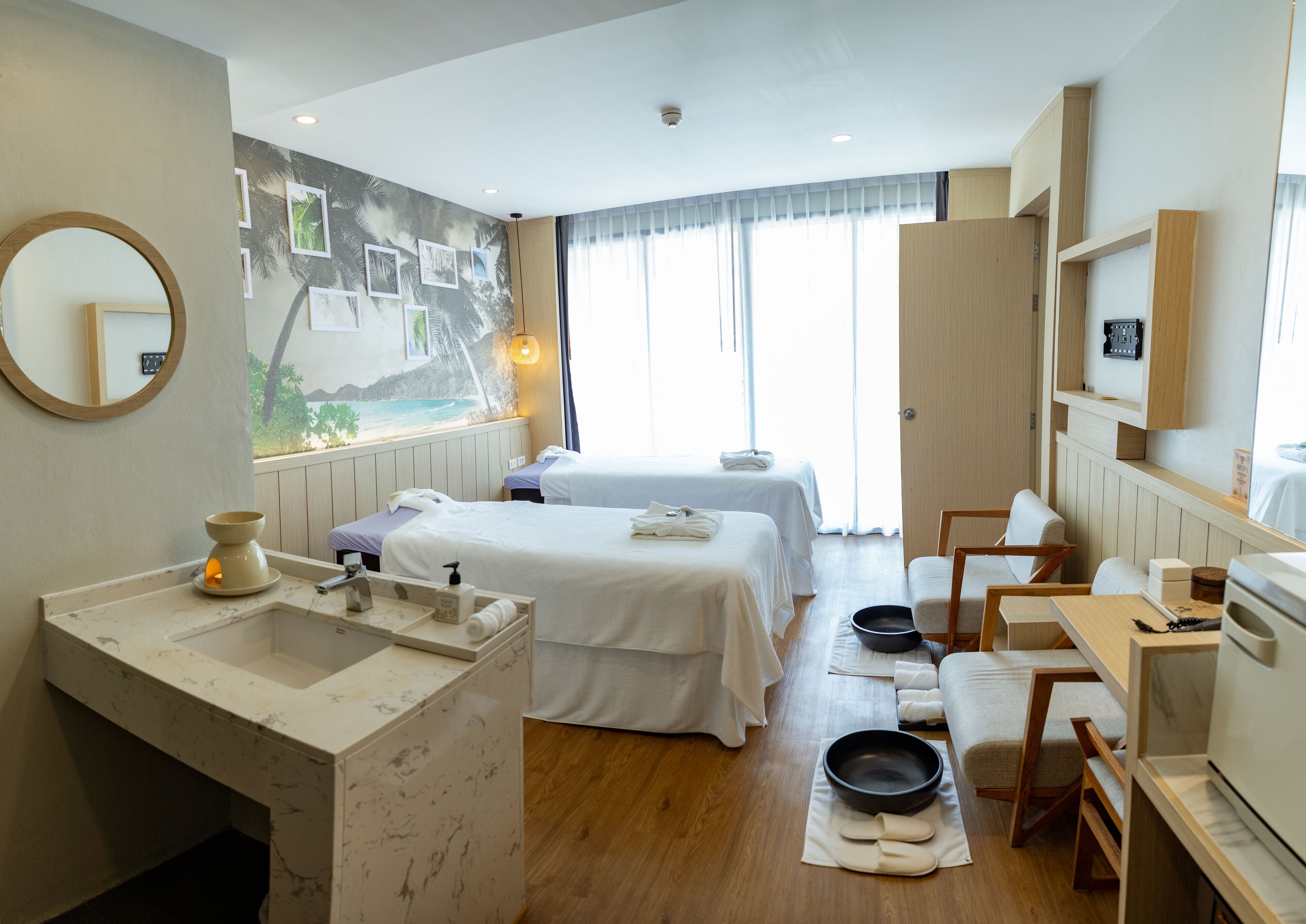 A hotel room with two beds, a bathroom with a marble sink, a dining area, and a mural on the wall.