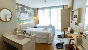 A hotel room with two beds, a bathroom with a marble sink, a dining area, and a mural on the wall.