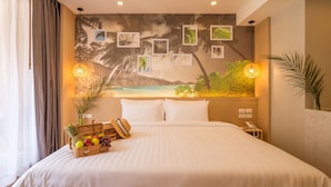 Habitación de hotel con una cama grande, un mural en la pared, dos lámparas de noche, una cesta de frutas y un teléfono.