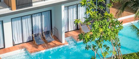 Un hotel moderno con zona de piscina, que incluye una terraza de madera y sillones de descanso.
