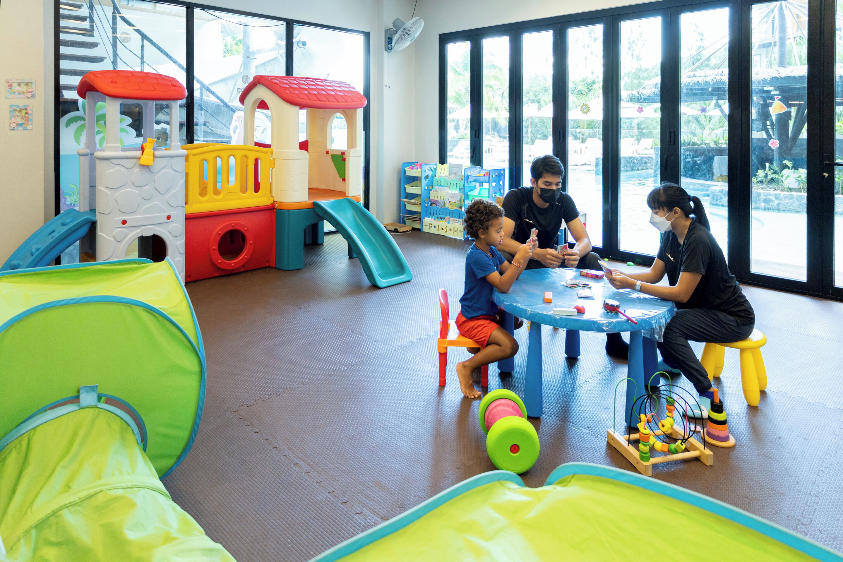 A play area with a slide, play structures, and a table with toys.