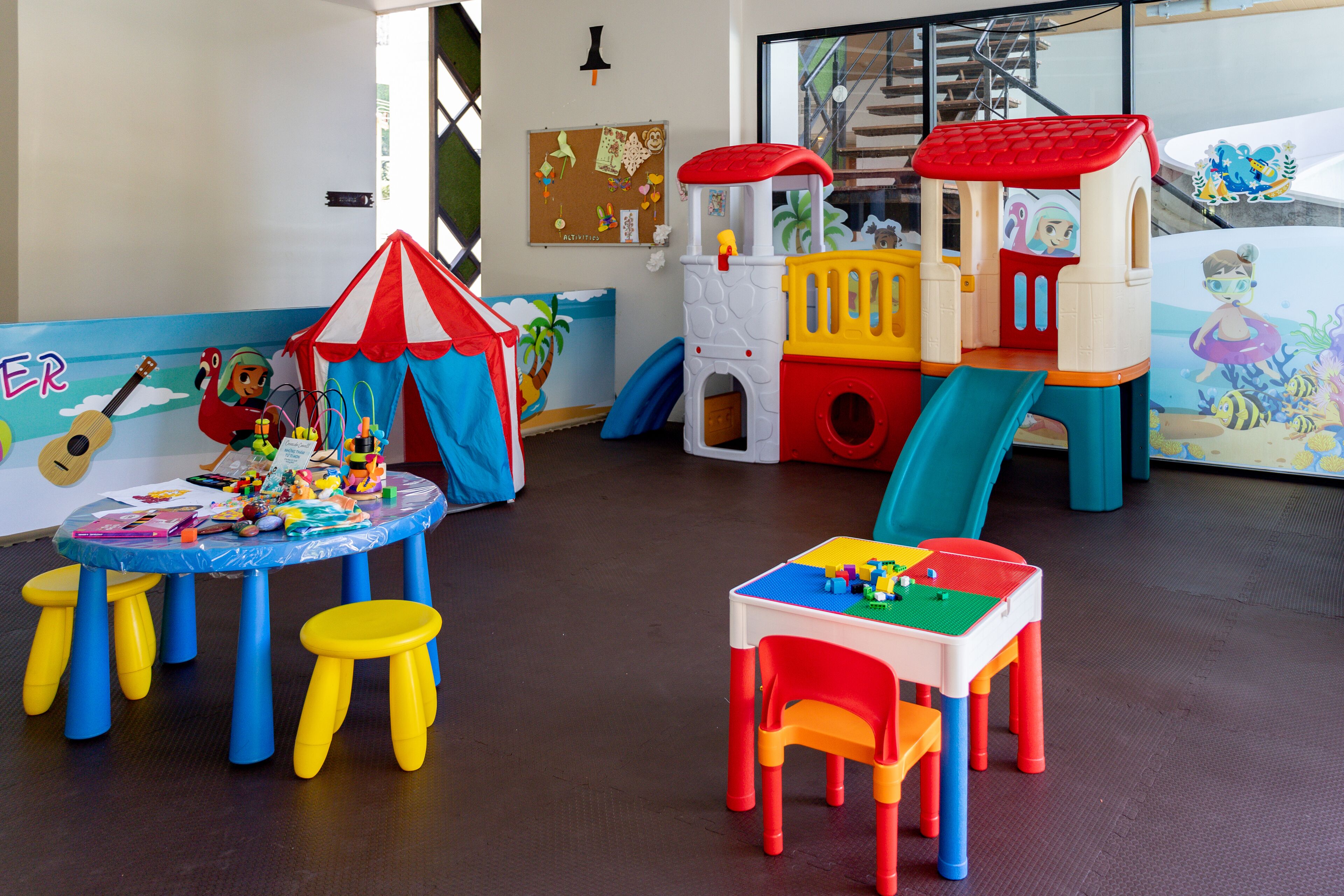 A children's play area with a playhouse, slides, and a table with toys.