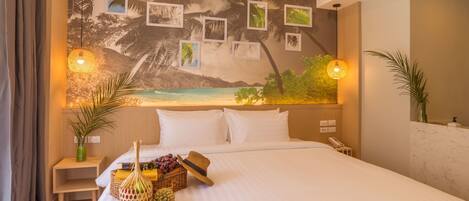 Habitación de hotel con una cama grande, un mural en la pared con playa y dos lámparas de noche.