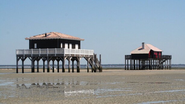Two wooden pier structures with upper decks, one with a red roof and the other with a tiled roof. - Bassin d'arcachon, a cozy little nest between dune du pyla and cap-ferret  (Audenge)