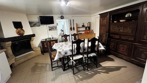 Un comedor con una mesa dispuesta para cuatro, una chimenea y un televisor montado en la pared.