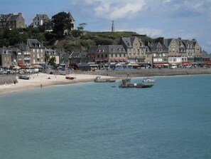 A coastal town with historic buildings, a sandy beach, and boats in the water.