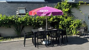 Un patio al aire libre con mesa y sillas, una sombrilla y una parrilla.