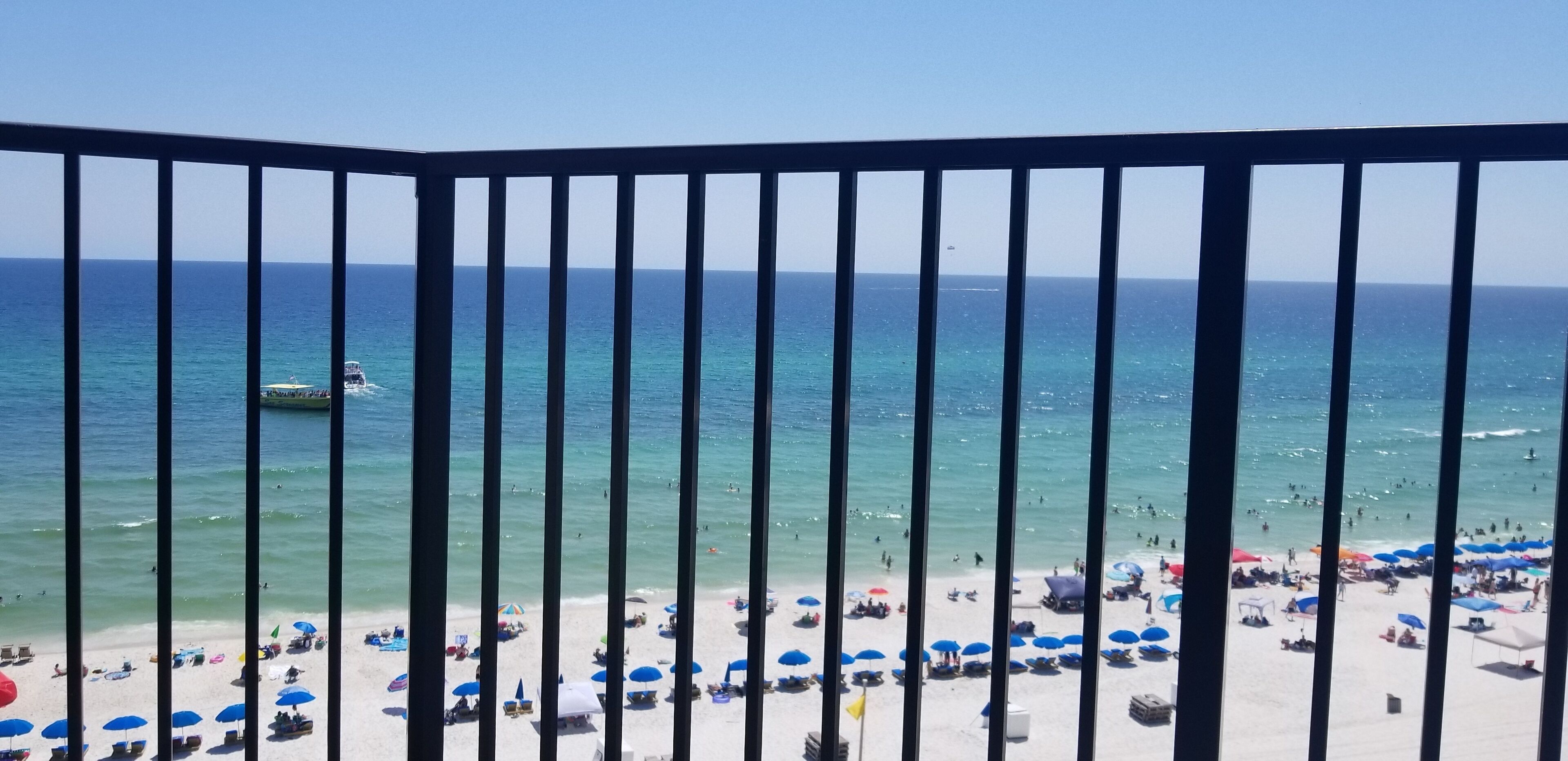 Ein Strand mit freiem Blick auf das Meer, ein Boot im Wasser sowie zahlreiche Sonnenschirme und Liegestühle.