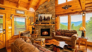 A log cabin interior with a fireplace, wooden furniture, and a stone wall. - A+ Views & Location! > Parkway, Dollywood. Theater, Hot Tub, Games, Pet Friendly (Pigeon Forge)