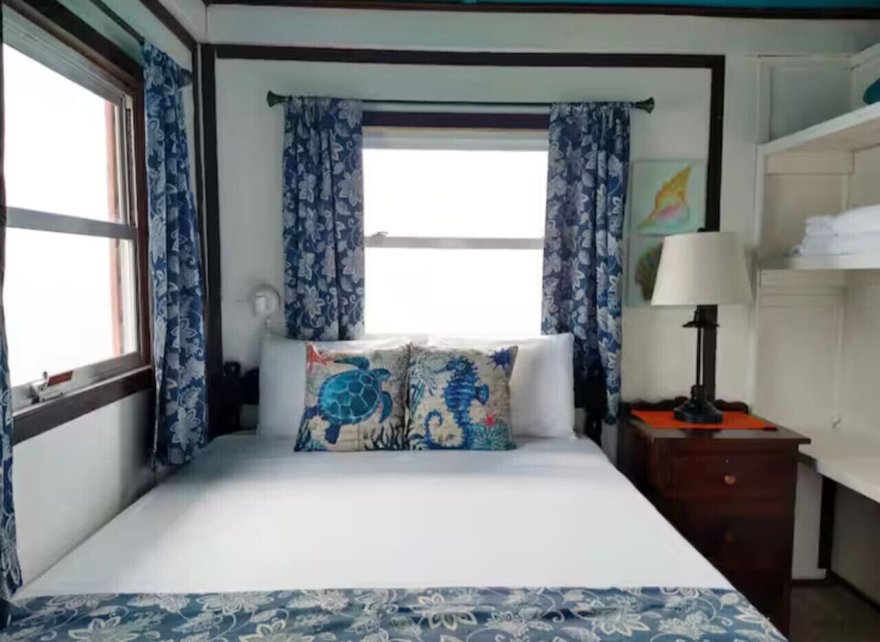 A bedroom with a bed, curtains, a nightstand, and a lamp.