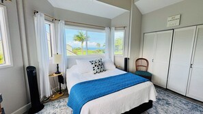 Une chambre à coucher comprenant un lit, une chaise, une table de chevet, une lampe et une vue sur l’extérieur.