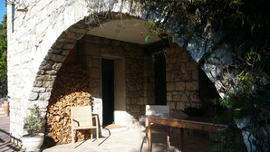 Un patio al aire libre con paredes de piedra, una mesa de madera y sillas.