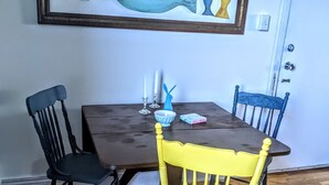 Une table à manger avec des chaises, un tableau représentant un poisson et une porte.