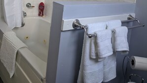 Une salle de bain équipée d’une baignoire, d’une douche, d’un porte-serviettes et d’un support à papier toilette.