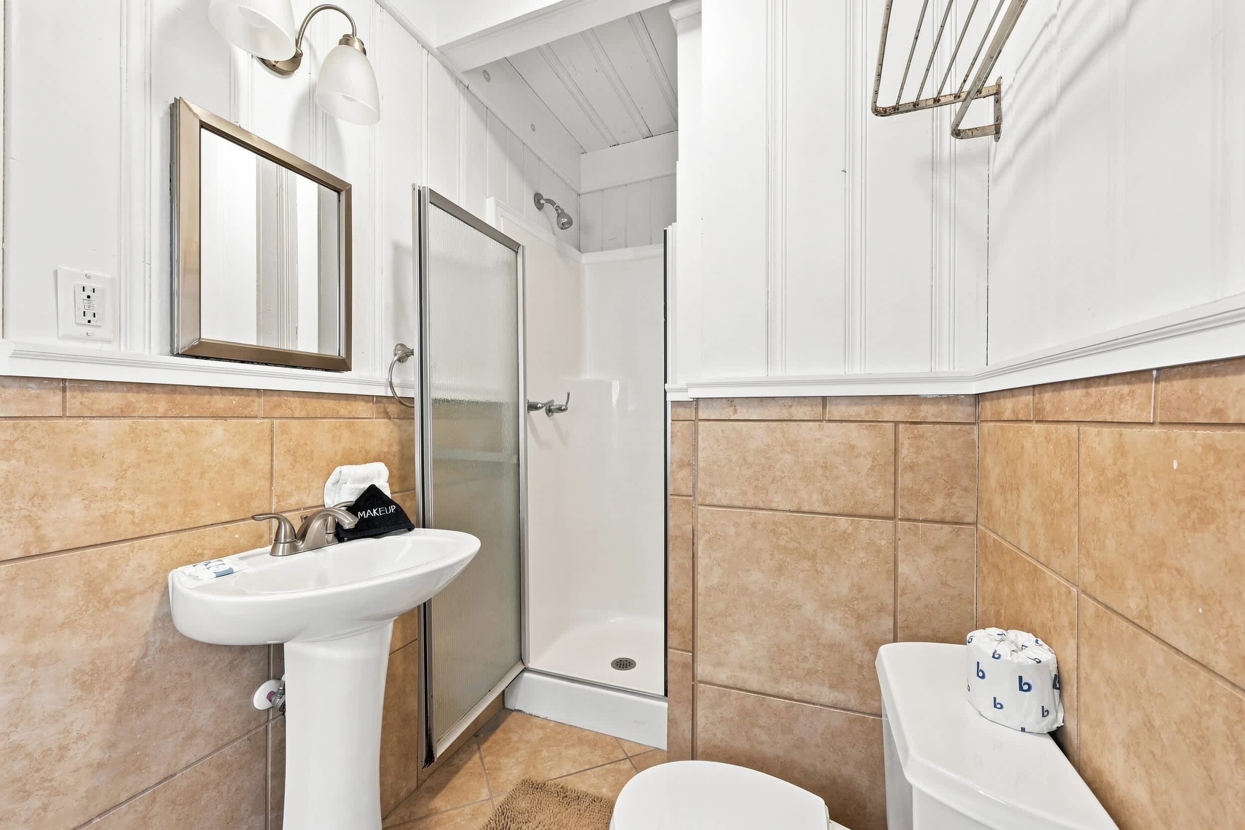 A bathroom with a white sink, a toilet, a shower, and a mirror.