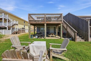 A covered outdoor patio area with a table and chairs, a barbecue grill, and a wooden deck. - Direct Oceanfront House Ocean and Pier Views (North Myrtle Beach)