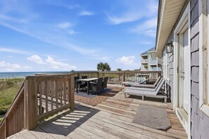 A wooden deck with outdoor furniture, a view of the ocean, and a building with a balcony. - Direct Oceanfront House Ocean and Pier Views (North Myrtle Beach)