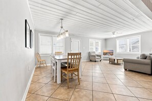 Un amplio espacio de sala con una mesa de comedor, sillas, un sofá y un televisor.