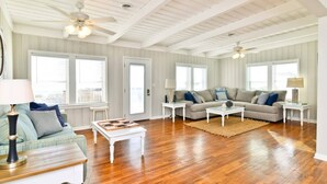 A spacious living room with wooden floors, two sofas, a coffee table, and a ceiling fan.