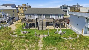 A two-story building with a central staircase, a covered outdoor seating area, and a grassy yard. - Direct Oceanfront House Ocean and Pier Views (North Myrtle Beach)