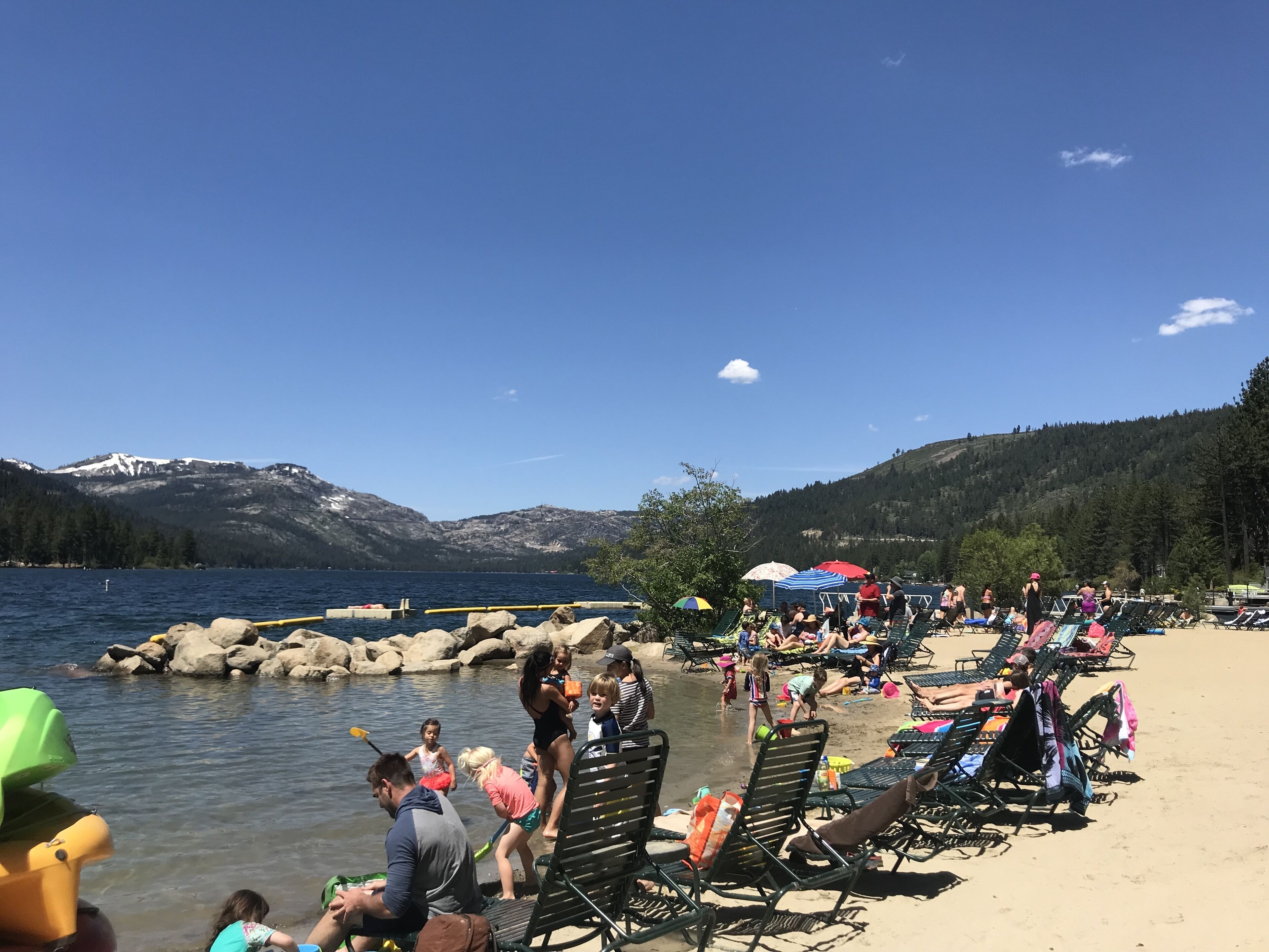 A beach with people, lounge chairs, and umbrellas.