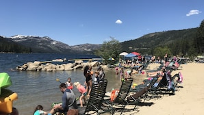 Una playa con gente, sillas de descanso y sombrillas.