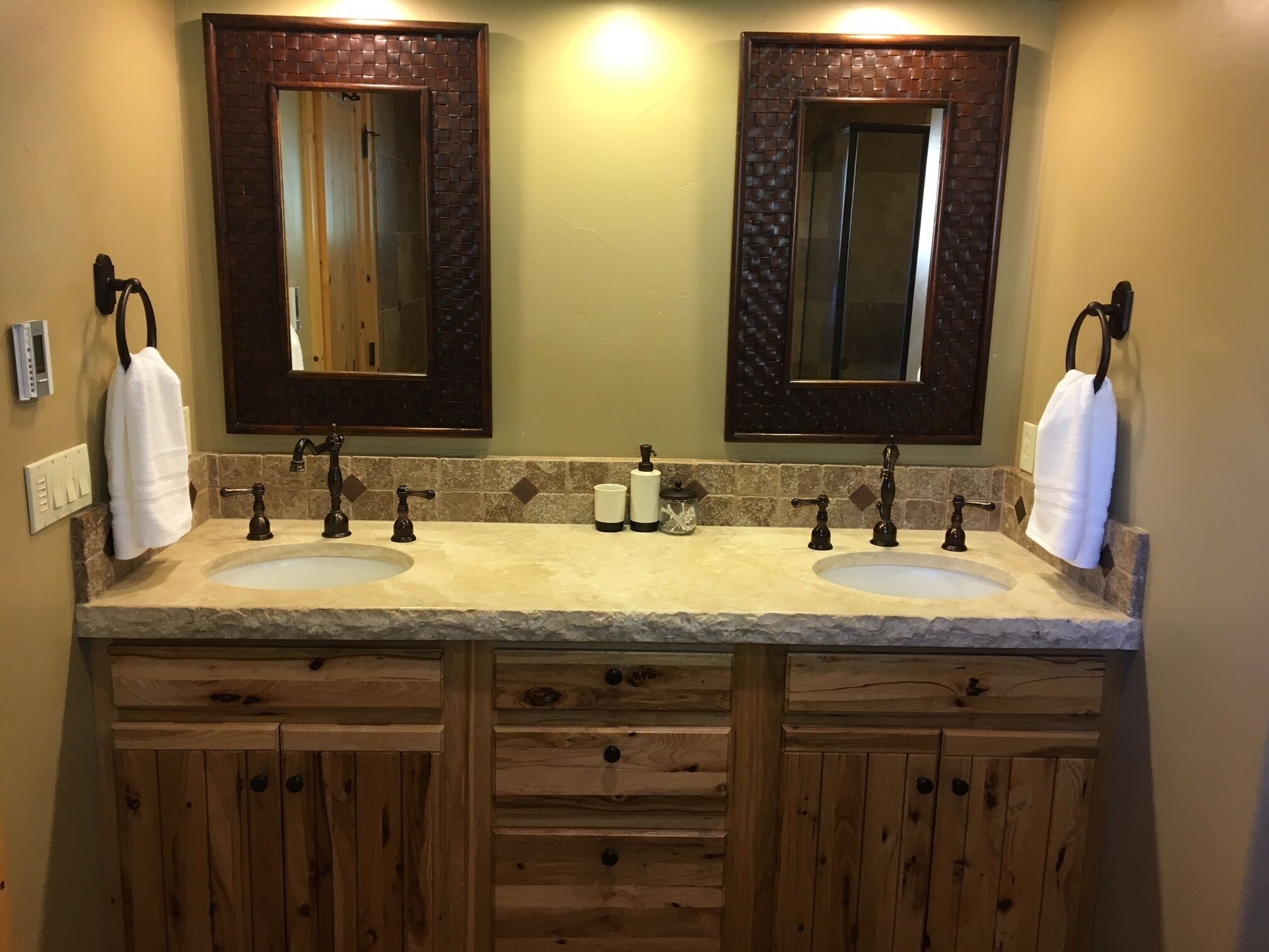 Un bagno con due lavandini, mobili in legno e due specchi con cornice a motivo di mattoni.