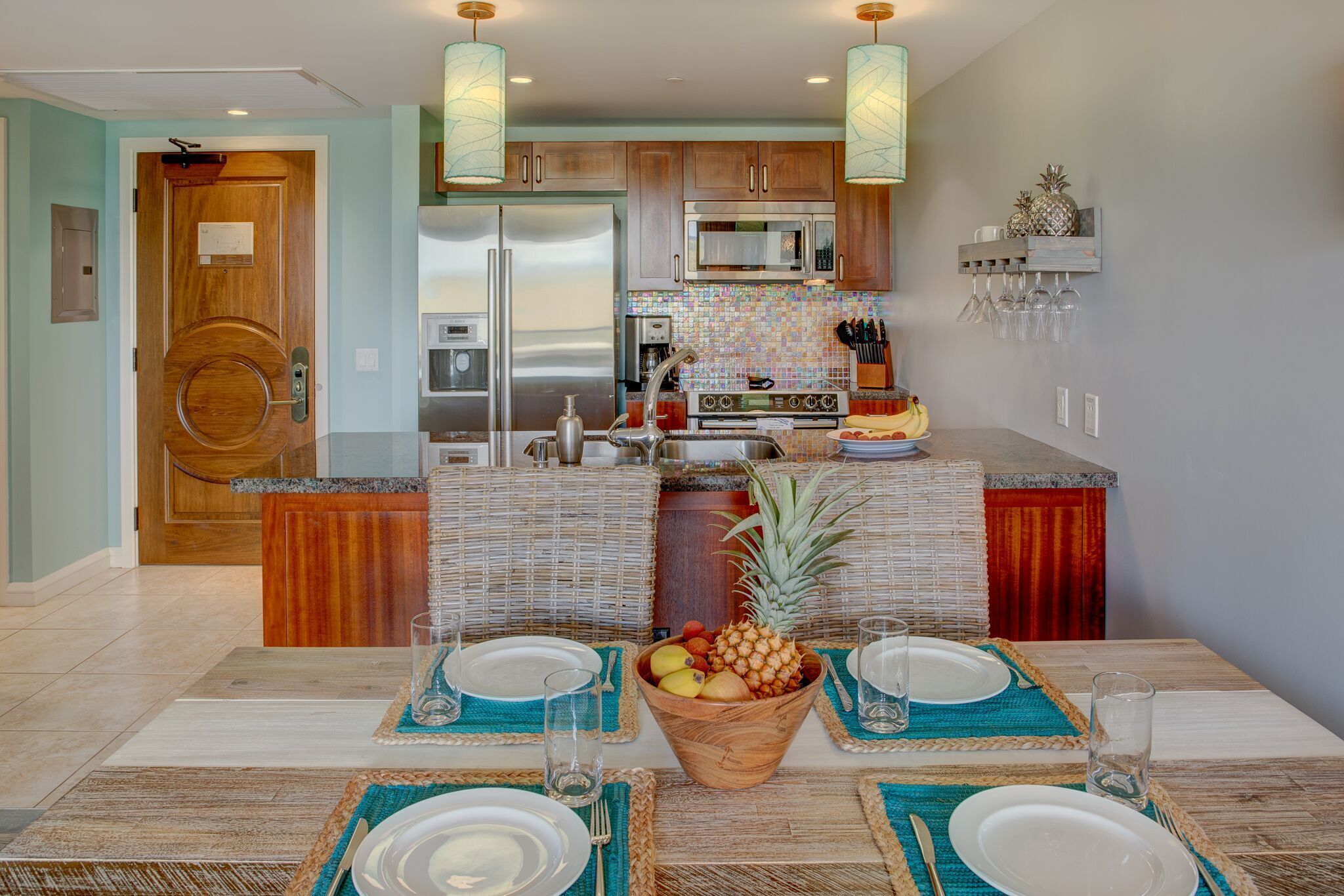 A modern kitchen with stainless steel appliances, a dining area with a central fruit bowl, and a breakfast bar.