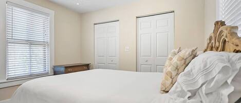 A bedroom with a bed, a dresser, two doors, and a ceiling fan.