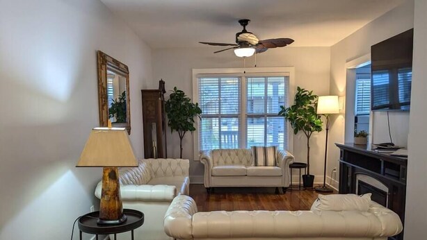 A living room with a ceiling fan, two sofas, a coffee table, a lamp, and a fireplace. - Downtown dog-friendly 4 bedroom house, walk everywhere, free parking (St Augustine)