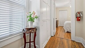 A hallway with a white door, a small table with a potted plant, and a fire extinguisher mounted on the wall. - Downtown dog-friendly 4 bedroom house, walk everywhere, free parking (St Augustine)