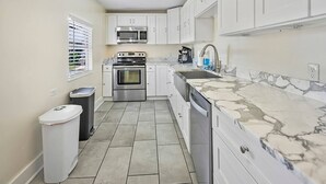 A modern kitchen with white cabinets, stainless steel appliances, and a marble countertop. - Downtown dog-friendly 4 bedroom house, walk everywhere, free parking (St Augustine)