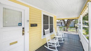 A porch with white rocking chairs, a white door with a mailbox, and a yellow wall with a window. - Downtown dog-friendly 4 bedroom house, walk everywhere, free parking (St Augustine)