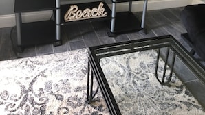 Una sala de estar con un televisor de pantalla plana sobre un soporte negro, un globo en una mesita y un letrero que dice 'Booth' en un estante.
