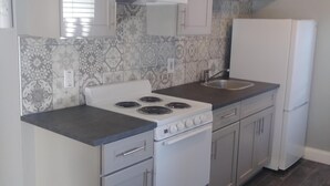 Una cocina compacta con armarios blancos, una estufa y un refrigerador.