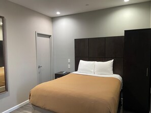 A bedroom with a bed, a nightstand, a wardrobe, and a door. - Baymont INN & Suites Long Island City (LONG ISLAND CITY)