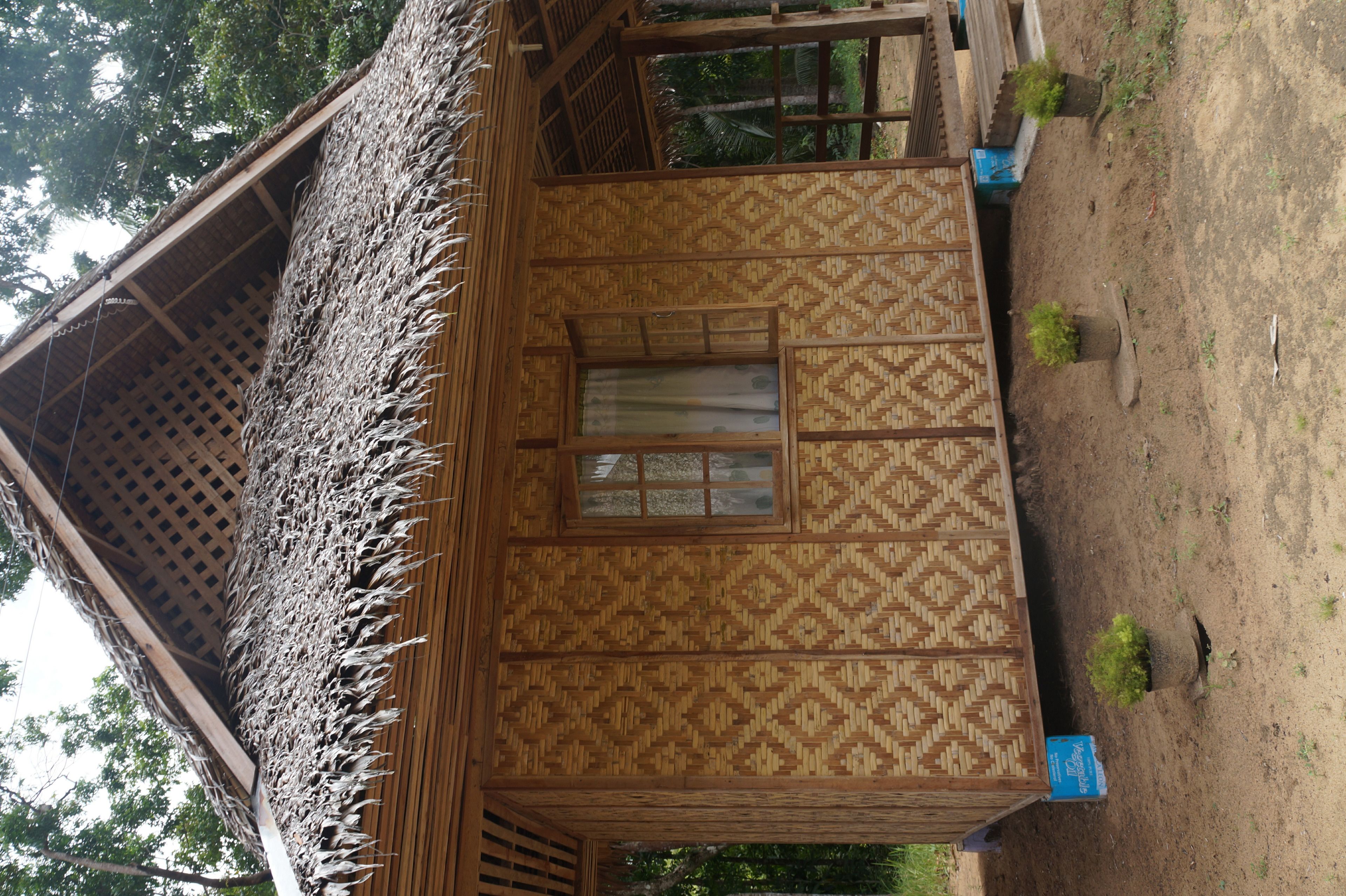 A thatched-roof hut with a patterned wall and a window.