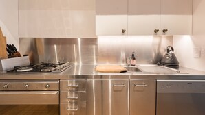 A modern kitchen with stainless steel appliances, a built-in oven, and a dishwasher. - The Designer's Residence (Auckland)