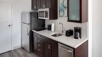 A modern kitchen with dark wooden cabinets, stainless steel appliances, a white countertop, and a dishwasher.