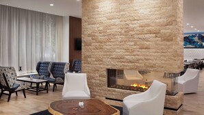 A modern lounge area with a stone wall, a fireplace, and comfortable seating. - Residence Inn Stamford Downtown (Stamford)