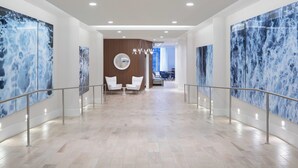 A spacious hallway with a marble floor, white chairs, and large blue marble wall panels. - Residence Inn Stamford Downtown (Stamford)