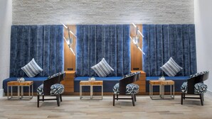A seating area with a sofa and chairs, a wooden table, and a blue curtain backdrop. - Residence Inn Stamford Downtown (Stamford)