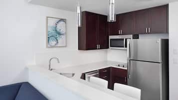 A modern kitchen with dark wooden cabinets, stainless steel appliances, and a white countertop.