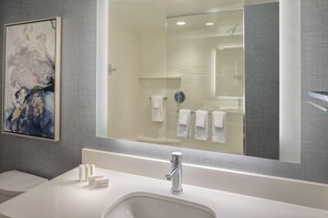 A modern bathroom with a large mirror, a white sink, and a glass-enclosed shower. - Residence Inn Stamford Downtown (Stamford)