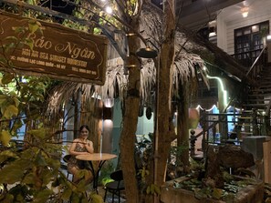 An indoor setting with a tropical theme, including a wooden sign, a table, chairs, and a hanging light fixture. - Hoi An Sea Sunset Villa & Bar (Da Nang)