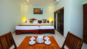 A hotel room with two beds, a table with tea sets, and a painting on the wall. - Hoi An Sea Sunset Villa & Bar (Da Nang)