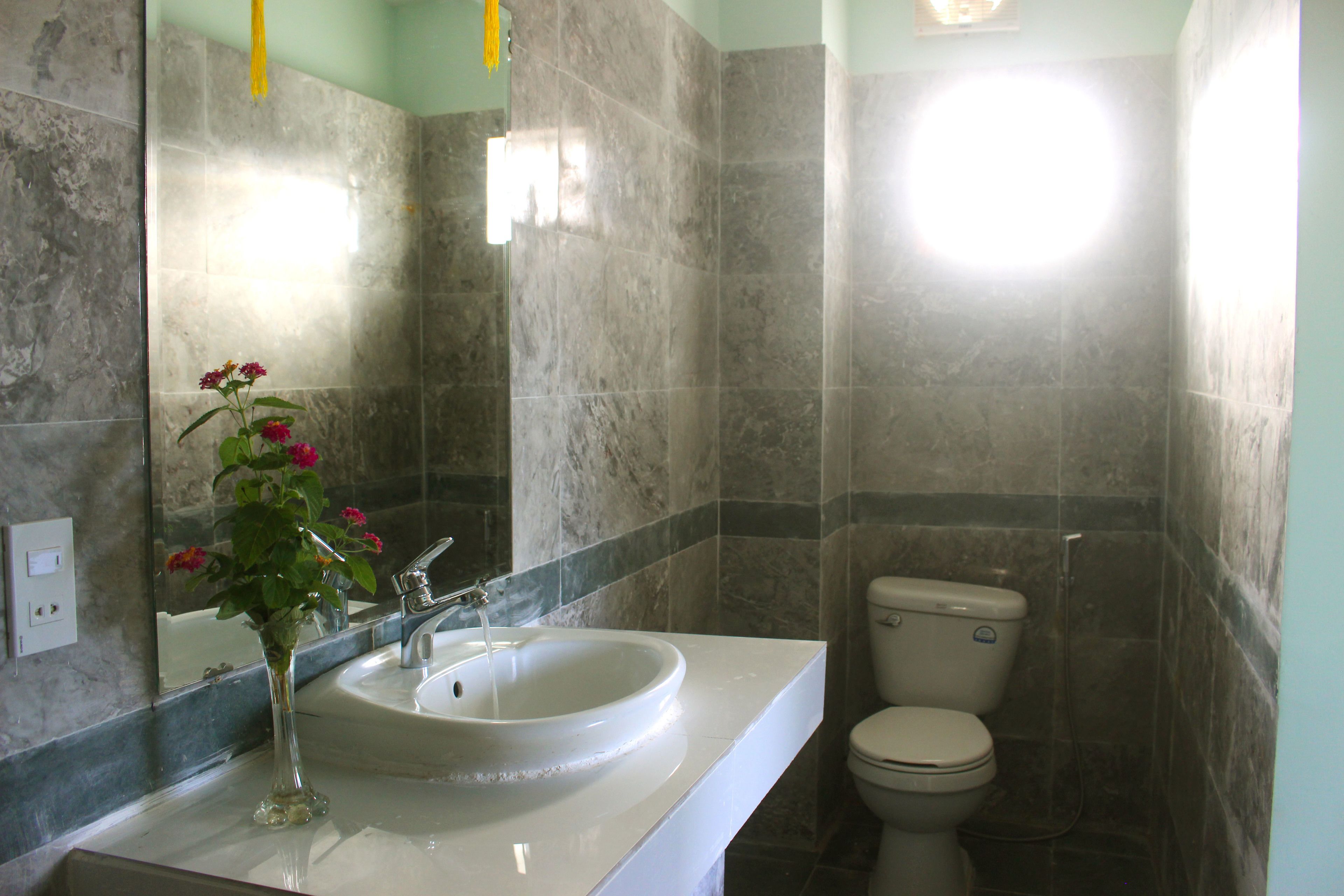 Un baño con lavamanos blanco, espejo y retrete.
