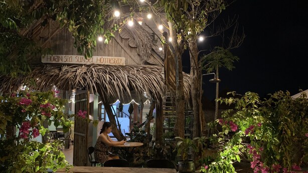 An outdoor seating area with a thatched roof, string lights, and potted plants. - Hoi An Sea Sunset Villa & Bar (Da Nang)